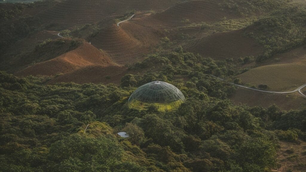An aerial view of a dome used for 3D printing in the middle of a mountain.